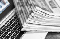 Laptop und Zeitungen als Symbol für eine Pressemeldung